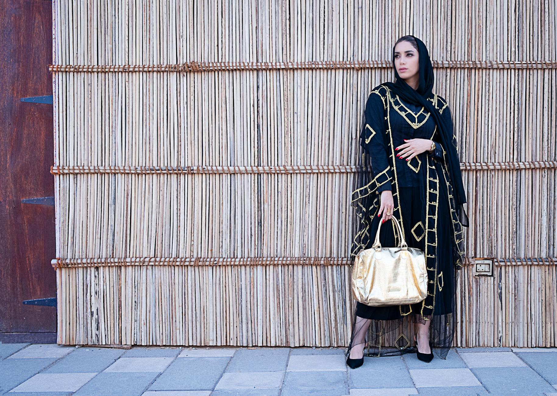 woman in blue and beige long sleeved dress holding a yellow bag