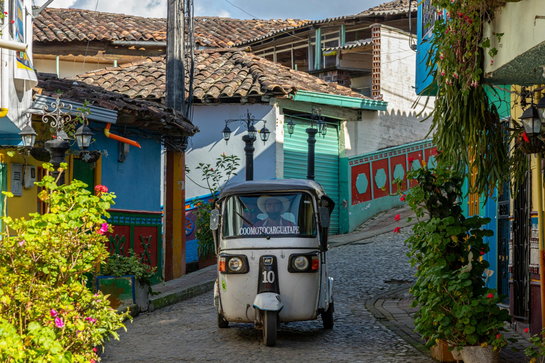 a three wheeler motorcycle moving on the street between concrete houses