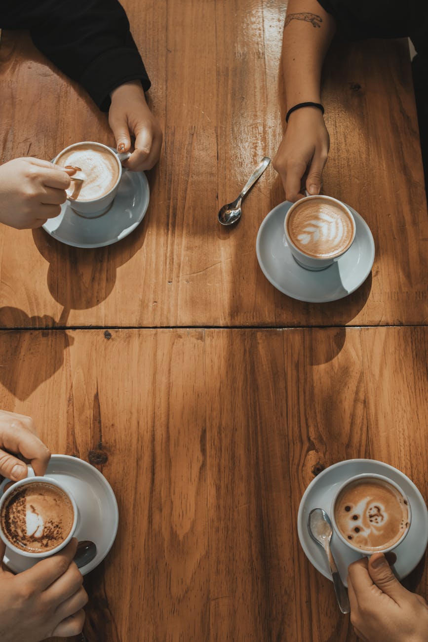 top view of people sitting at a table in a cafe with coffees