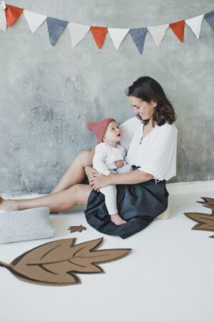 woman in white top and black skirt sitting on a pillow with her baby