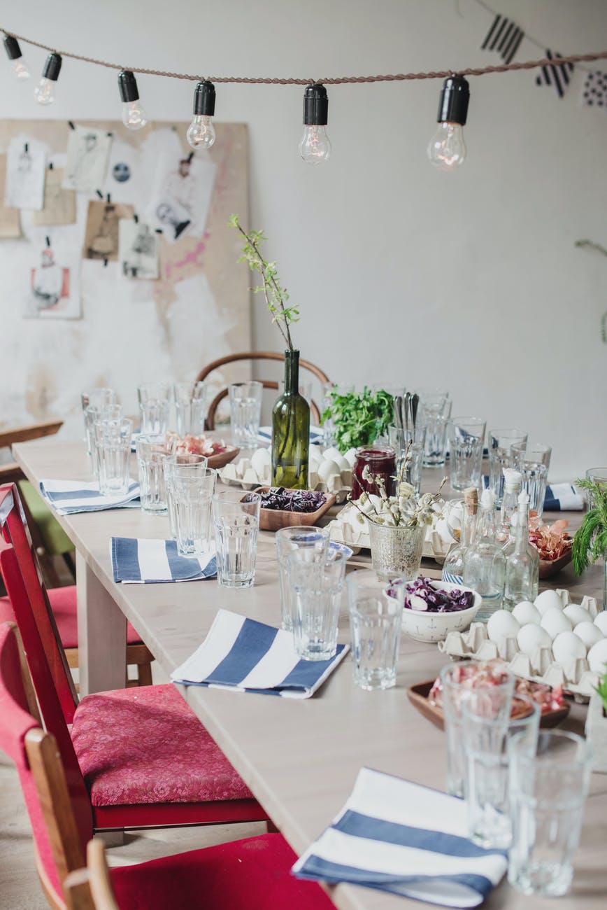 decorated room with banquet table served for celebration of easter with green tree branch in vine bottle and eggs