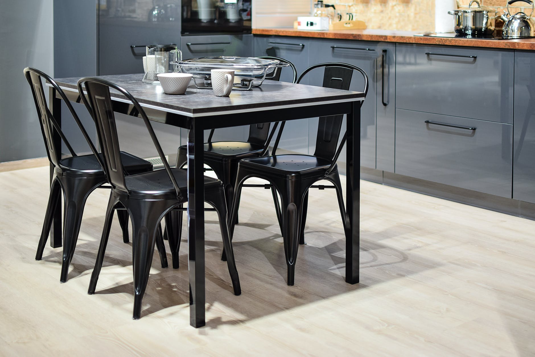 white ceramic mug on black dining table with four chair set